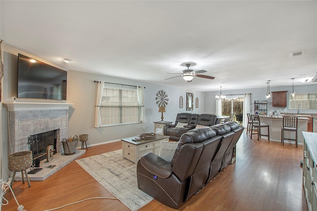 living room with a healthy amount of sunlight, visible vents, a fireplace, and wood finished floors