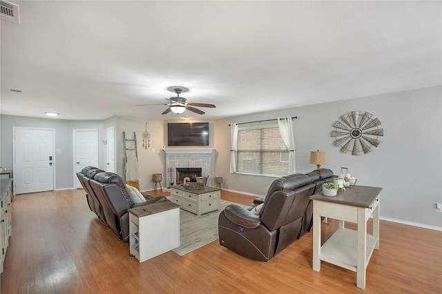 living area with light wood-style floors, baseboards, a fireplace, and visible vents