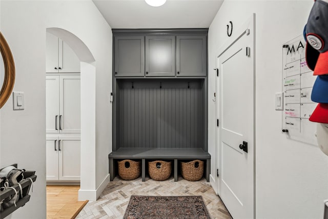 mudroom with parquet floors, baseboards, and arched walkways