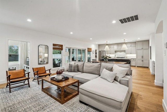 living area with baseboards, light wood finished floors, visible vents, and recessed lighting