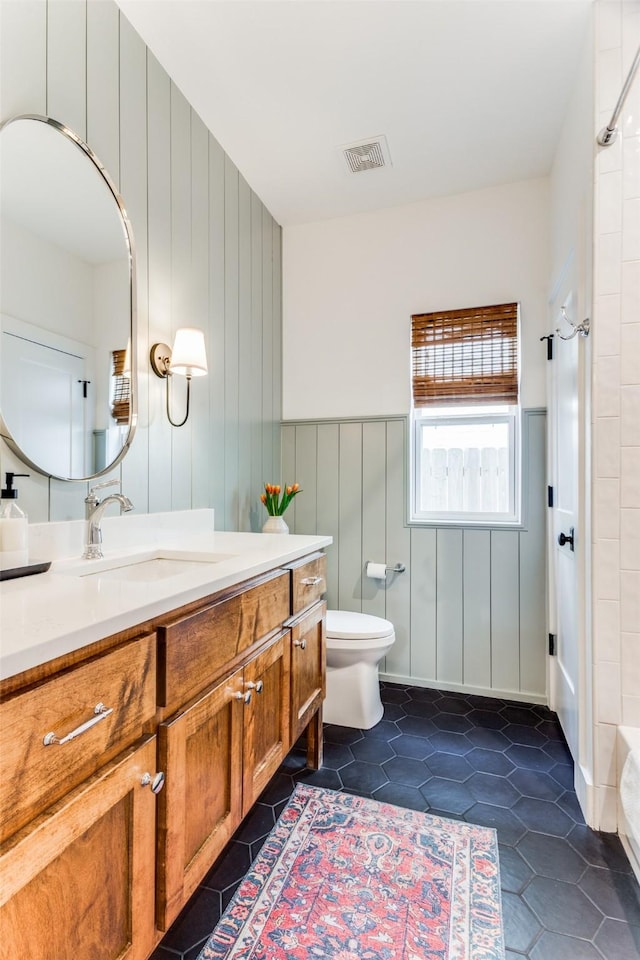 bathroom featuring tile patterned flooring, toilet, a wainscoted wall, vanity, and visible vents