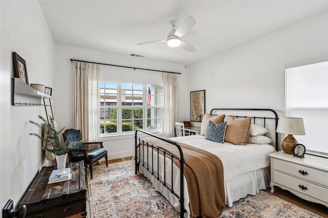 bedroom with baseboards, ceiling fan, visible vents, and wood finished floors