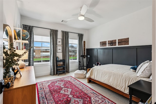 carpeted bedroom featuring visible vents, ceiling fan, and a decorative wall