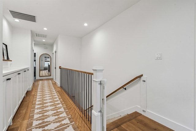 hallway with light wood-type flooring, recessed lighting, visible vents, and an upstairs landing