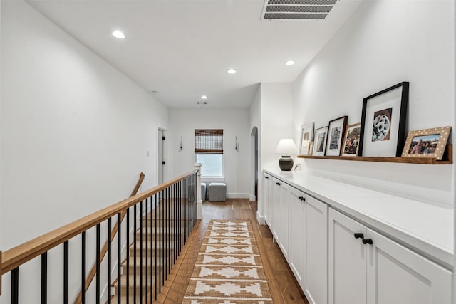 hall with light wood-type flooring, visible vents, an upstairs landing, and recessed lighting