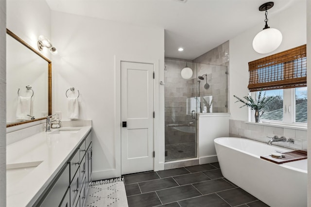 full bath with double vanity, a sink, a shower stall, tile patterned flooring, and a freestanding tub