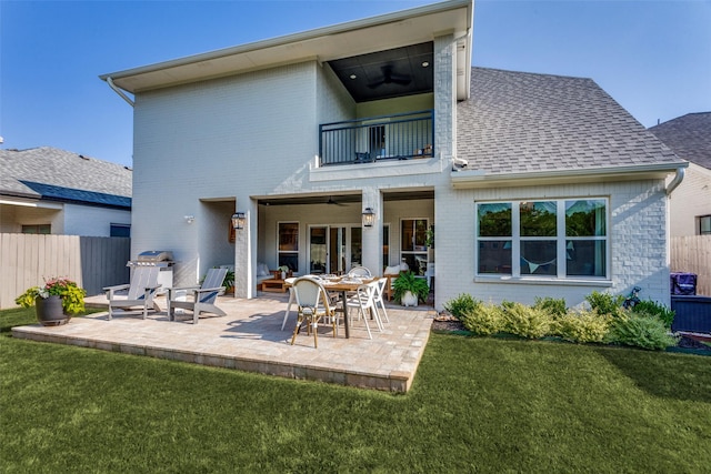 rear view of property with a yard, brick siding, fence, and a balcony