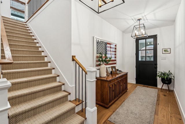 entrance foyer featuring baseboards, stairs, light wood-style flooring, and an inviting chandelier