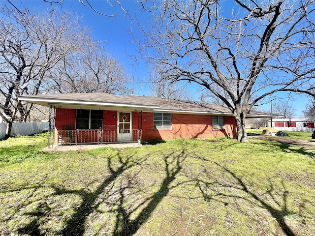 ranch-style home featuring covered porch, a front yard, fence, and brick siding