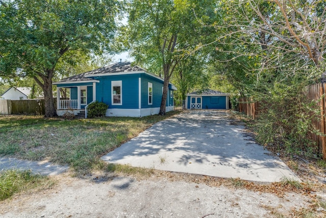 view of front of home with a porch, an outdoor structure, fence, driveway, and a shed