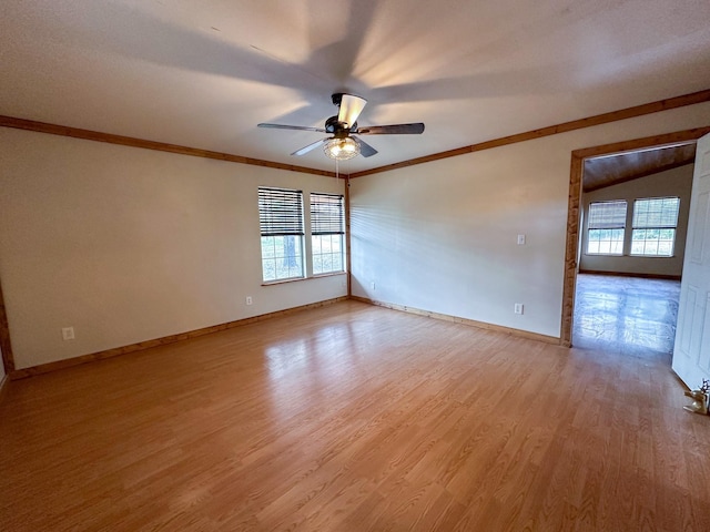 empty room featuring plenty of natural light, light wood-type flooring, baseboards, and crown molding