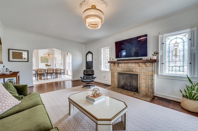 living area with arched walkways, plenty of natural light, and wood finished floors