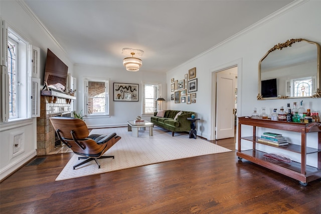 sitting room with baseboards, visible vents, wood finished floors, and ornamental molding