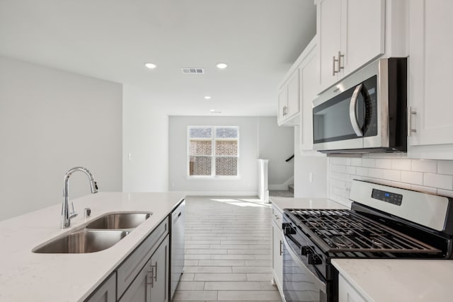 kitchen featuring stainless steel appliances, tasteful backsplash, visible vents, white cabinetry, and a sink