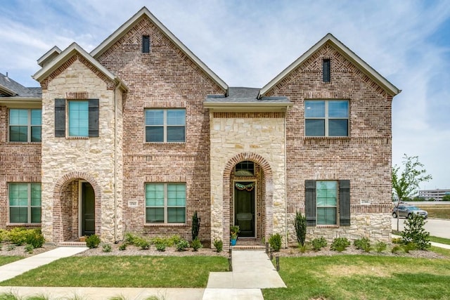 multi unit property with stone siding, brick siding, and a front lawn