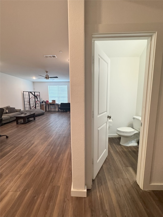 corridor with dark wood-type flooring, visible vents, and baseboards