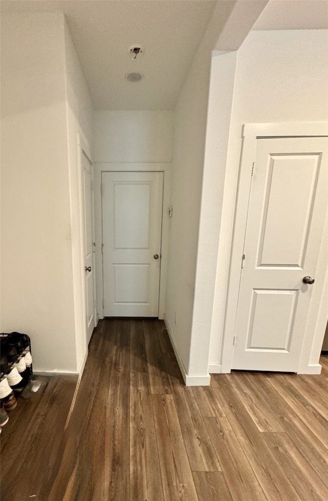 corridor with baseboards and wood finished floors