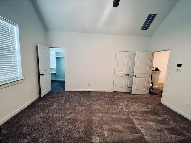 unfurnished bedroom with lofted ceiling, a closet, carpet flooring, and baseboards