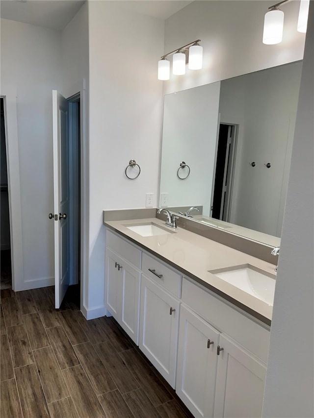 bathroom featuring double vanity, wood tiled floor, baseboards, and a sink