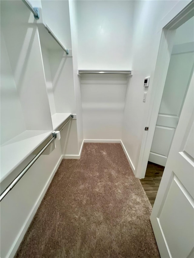 walk in closet featuring dark carpet