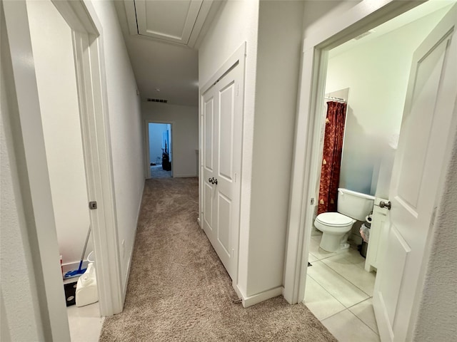 corridor featuring light carpet, light tile patterned flooring, and visible vents