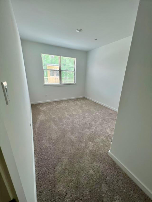 spare room featuring carpet floors and baseboards