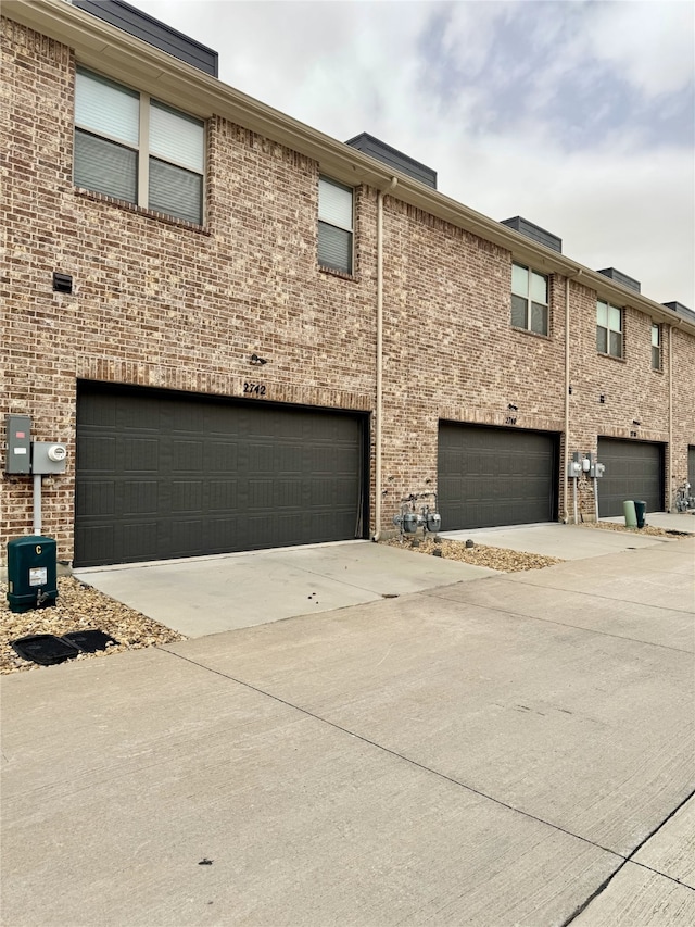 exterior space with a garage, brick siding, and driveway