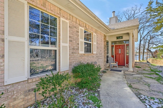 entrance to property featuring brick siding and a chimney