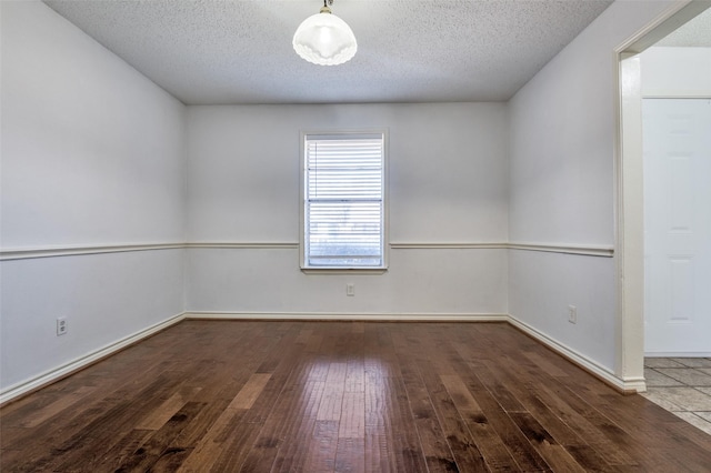 empty room with wood-type flooring, a textured ceiling, and baseboards