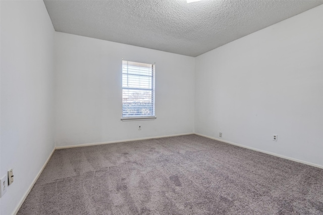 carpeted spare room featuring baseboards and a textured ceiling