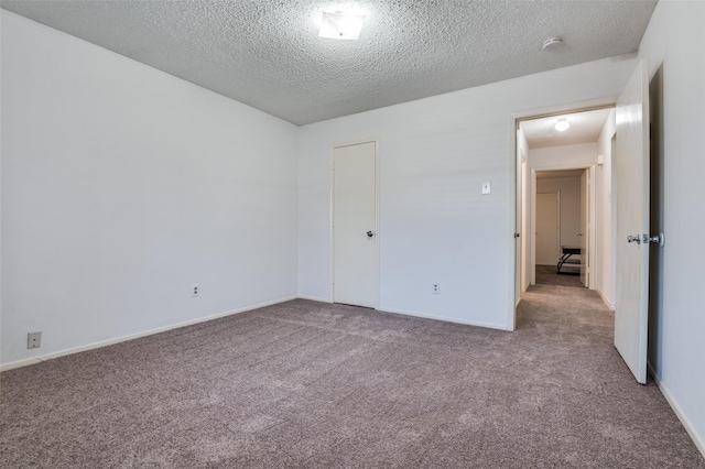 unfurnished bedroom with carpet floors, a textured ceiling, and baseboards