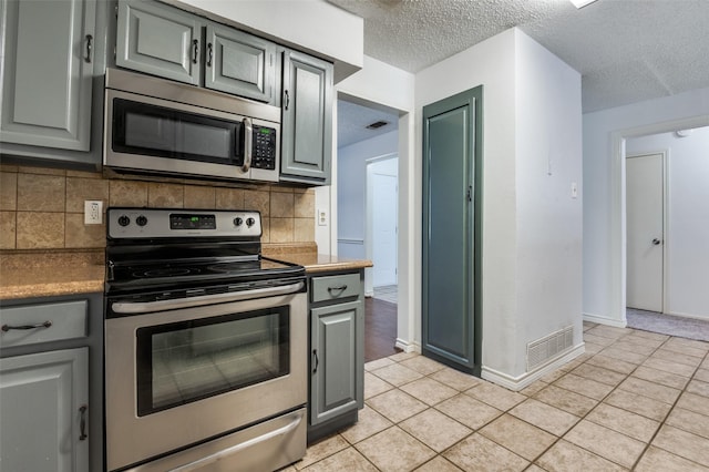 kitchen featuring light tile patterned floors, appliances with stainless steel finishes, and gray cabinets