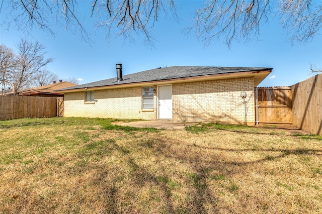 back of property featuring brick siding, a fenced backyard, and a yard