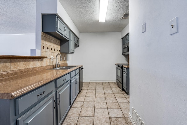 kitchen featuring light tile patterned floors, appliances with stainless steel finishes, a sink, and visible vents