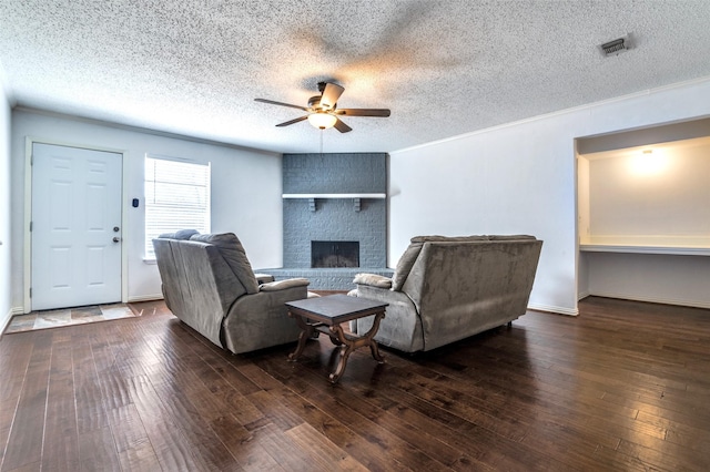 living area with ceiling fan, a fireplace, visible vents, and hardwood / wood-style floors