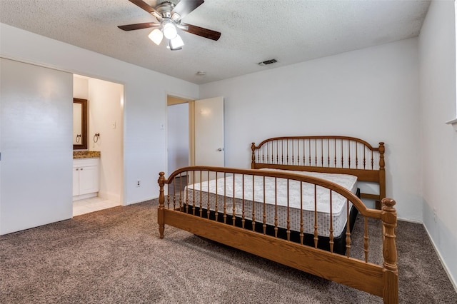 bedroom featuring visible vents, light carpet, a textured ceiling, and ensuite bathroom