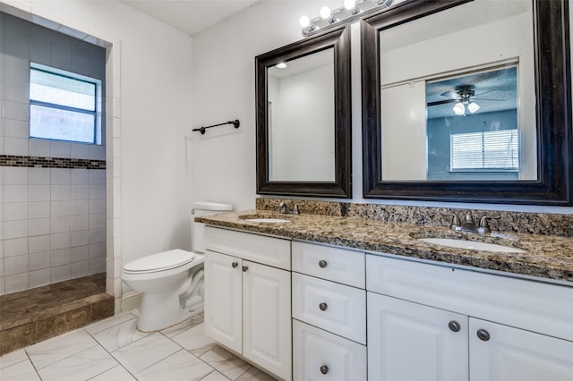 full bath with tiled shower, a sink, toilet, and double vanity