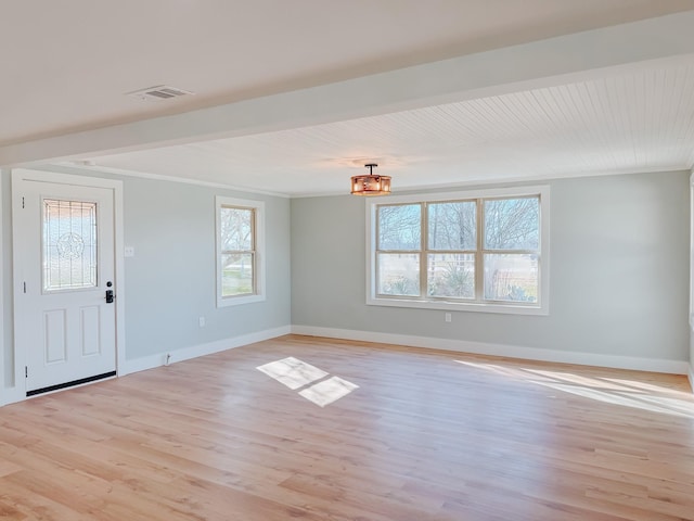 interior space featuring visible vents, light wood-style flooring, ornamental molding, beamed ceiling, and baseboards