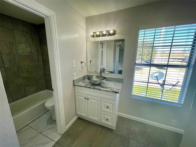 bathroom featuring a textured wall, toilet, vanity, and baseboards