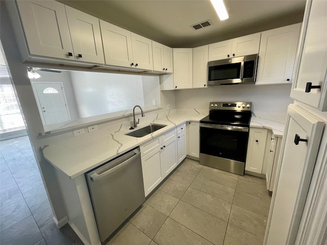 kitchen featuring a sink, visible vents, white cabinets, appliances with stainless steel finishes, and light stone countertops