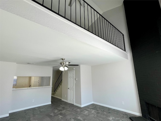 unfurnished living room featuring ceiling fan, stairway, visible vents, and baseboards