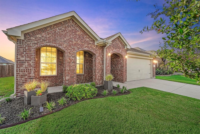 view of front of home featuring brick siding, driveway, an attached garage, and a lawn