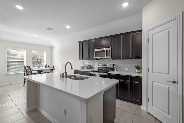 kitchen featuring light tile patterned floors, stainless steel appliances, visible vents, decorative backsplash, and a sink