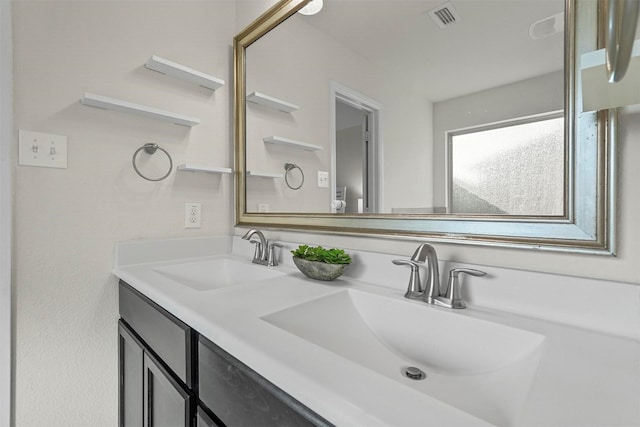 bathroom with visible vents, a sink, and double vanity