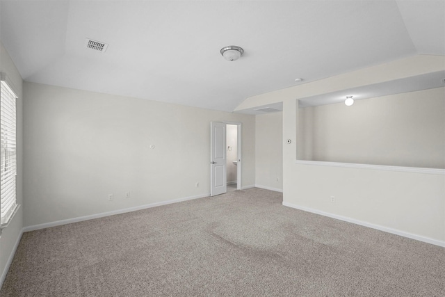 spare room featuring lofted ceiling, baseboards, visible vents, and carpet