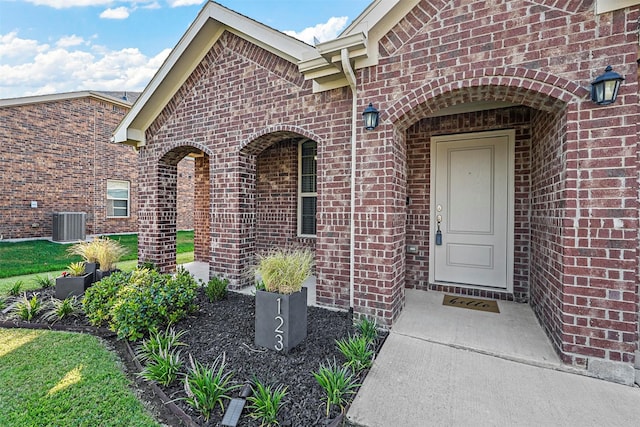 doorway to property with central AC unit and brick siding