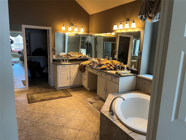 ensuite bathroom with vanity, vaulted ceiling, a bath, tile patterned floors, and ensuite bath