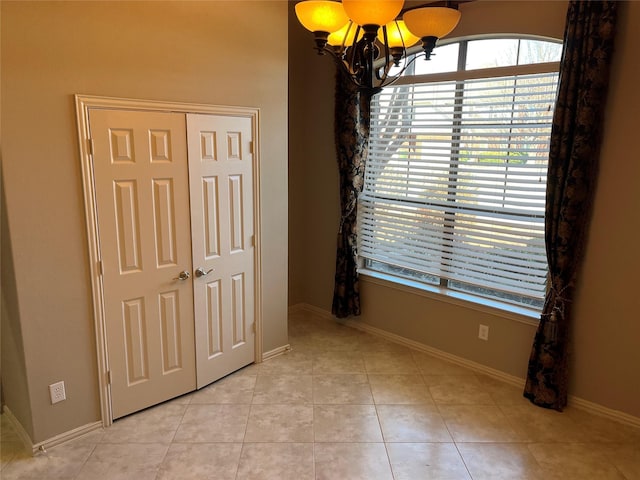 unfurnished room with light tile patterned floors, baseboards, and a notable chandelier