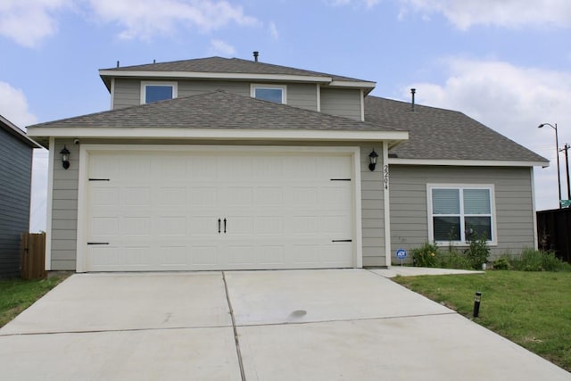 traditional-style home featuring roof with shingles, driveway, and an attached garage