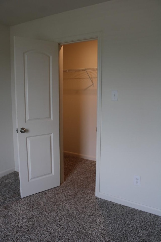 unfurnished bedroom featuring carpet, a closet, a spacious closet, and baseboards